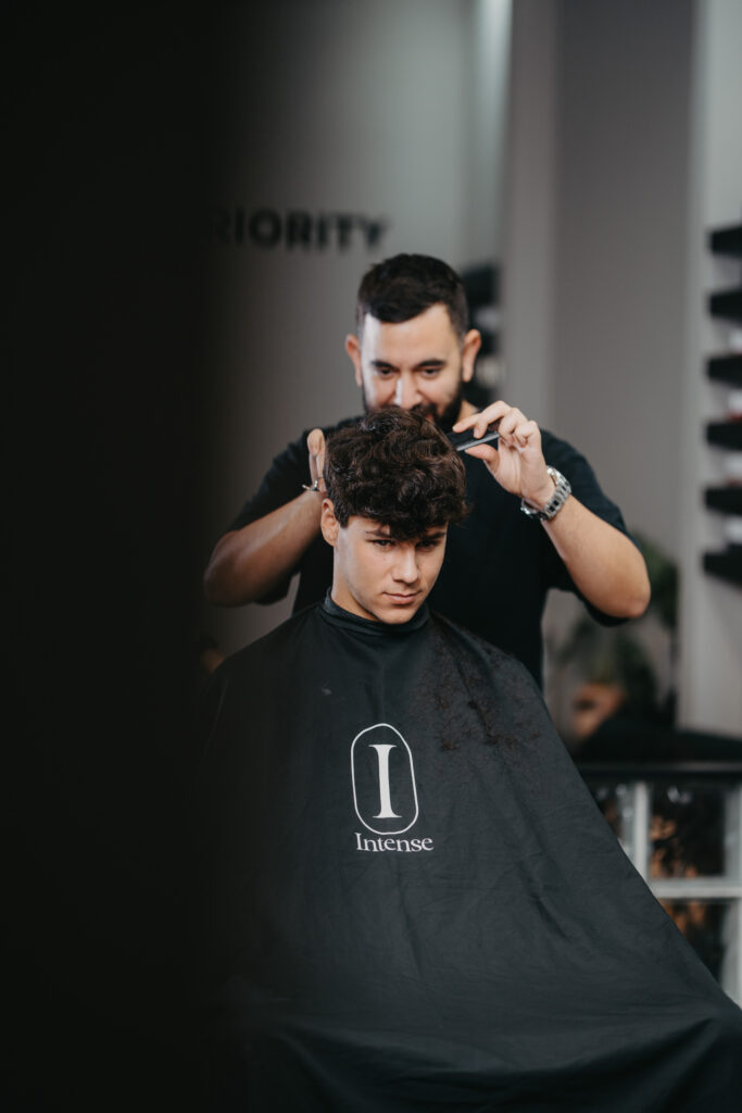 Professional barber providing a precision hair trim at Intense Grooming luxury men's salon in Amman.